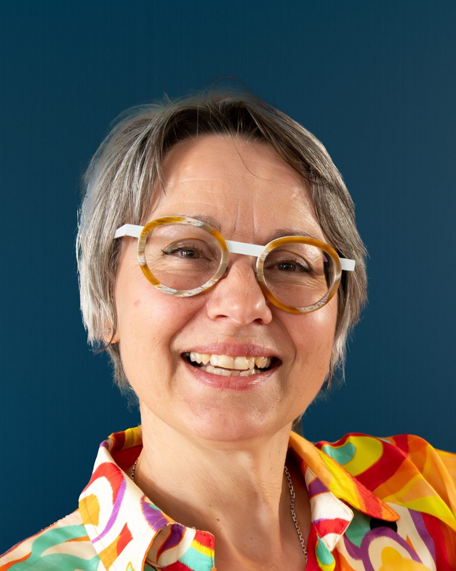 Portrait de Carole BOYER, naturopathe à Angoulême, souriante, avec des lunettes rondes et une chemise colorée